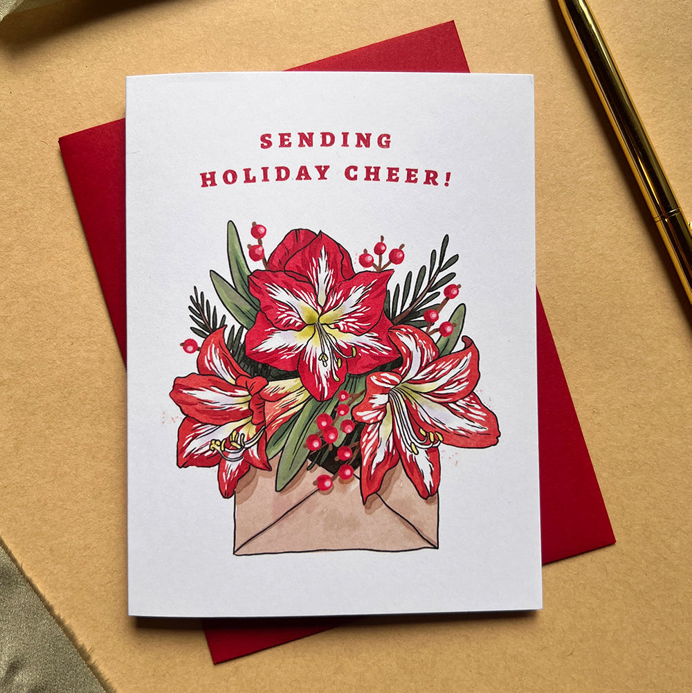 Greeting card with floral design and 'Sending Holiday Cheer!' text on a beige surface.