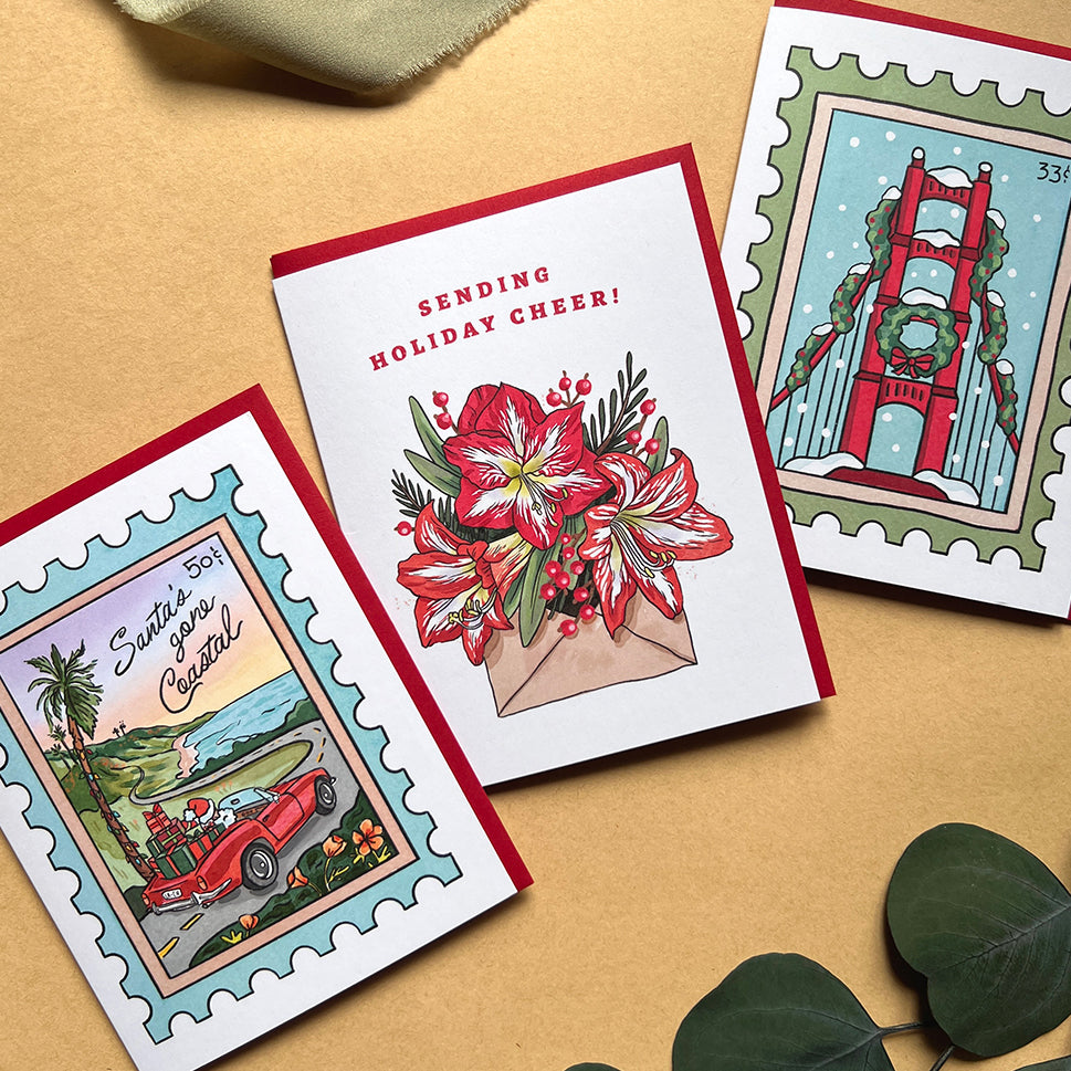 Three holiday greeting cards on a beige surface with decorative elements.