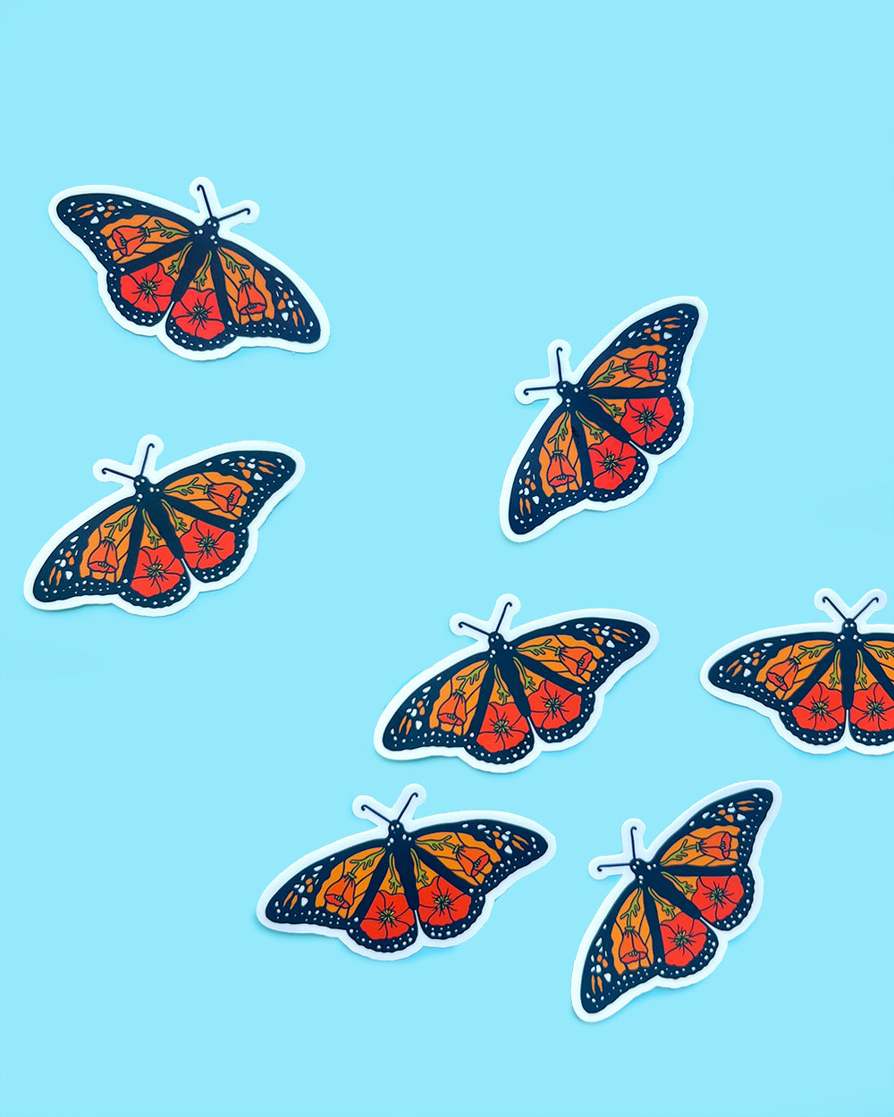 Several California monarch poppy stickers arranged on a blue background