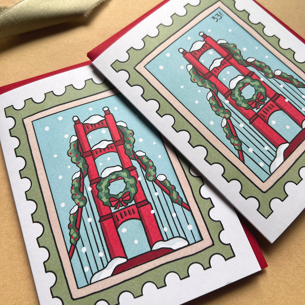 Two greeting cards with a festive Golden Gate Bridge design on a beige background.
