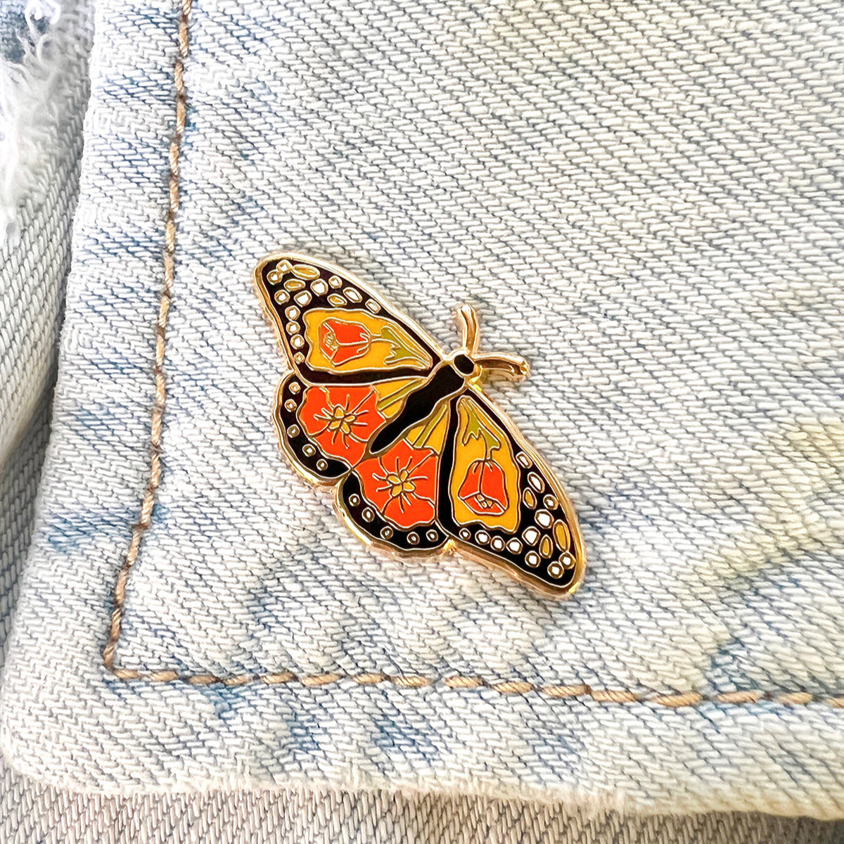 Monarch butterfly-shaped pin on a denim fabric background