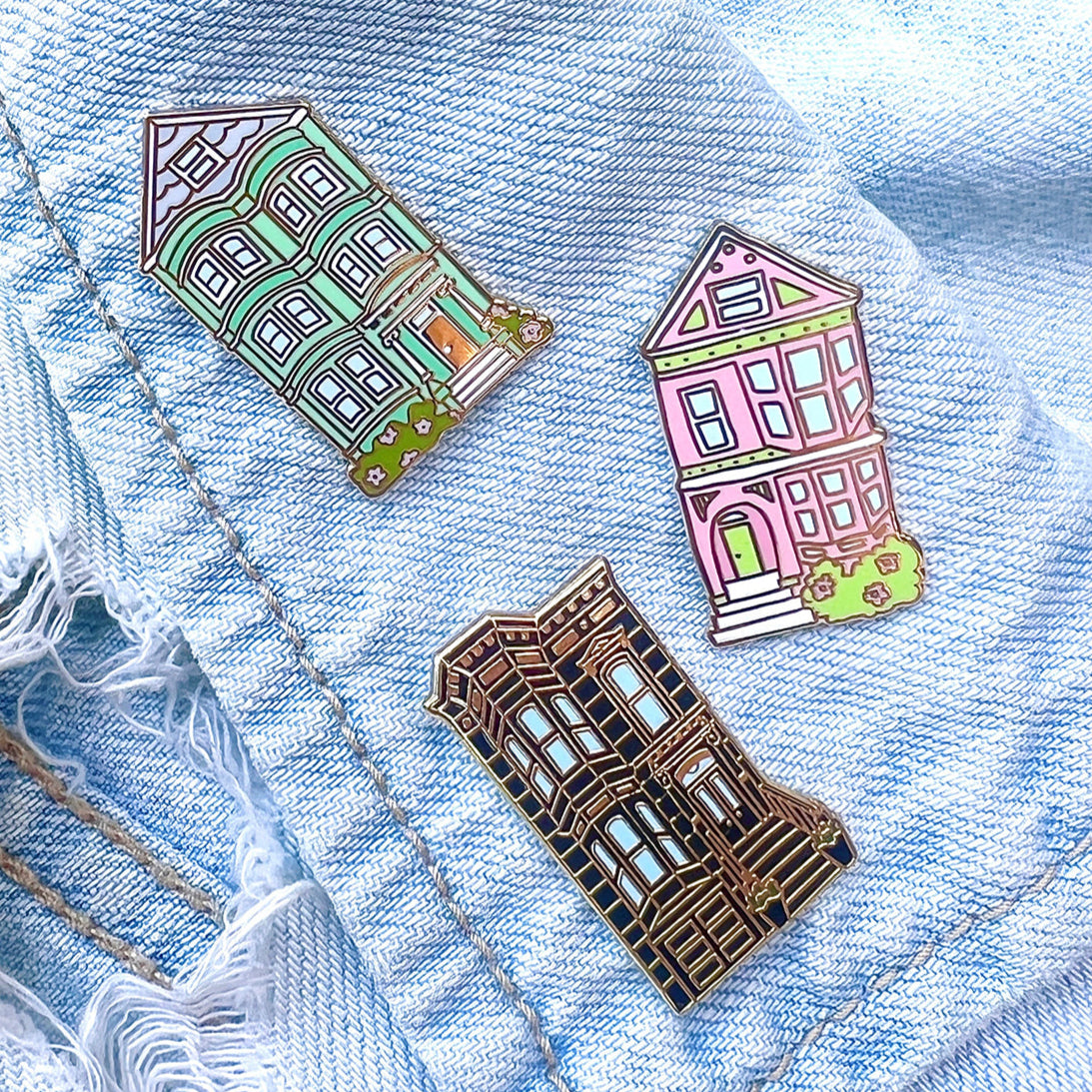 Three house-shaped pins on a denim background