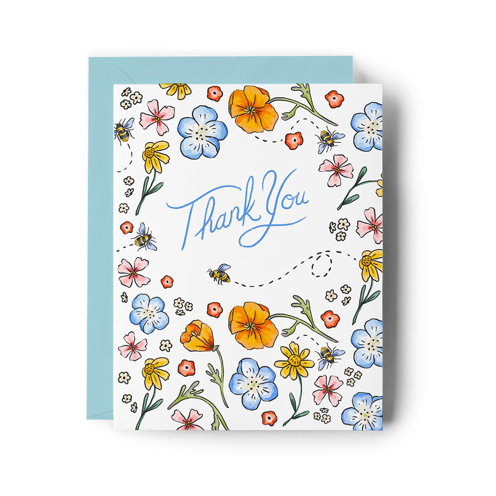 card with a wildflower and bee pattern and blue envelope on a white background