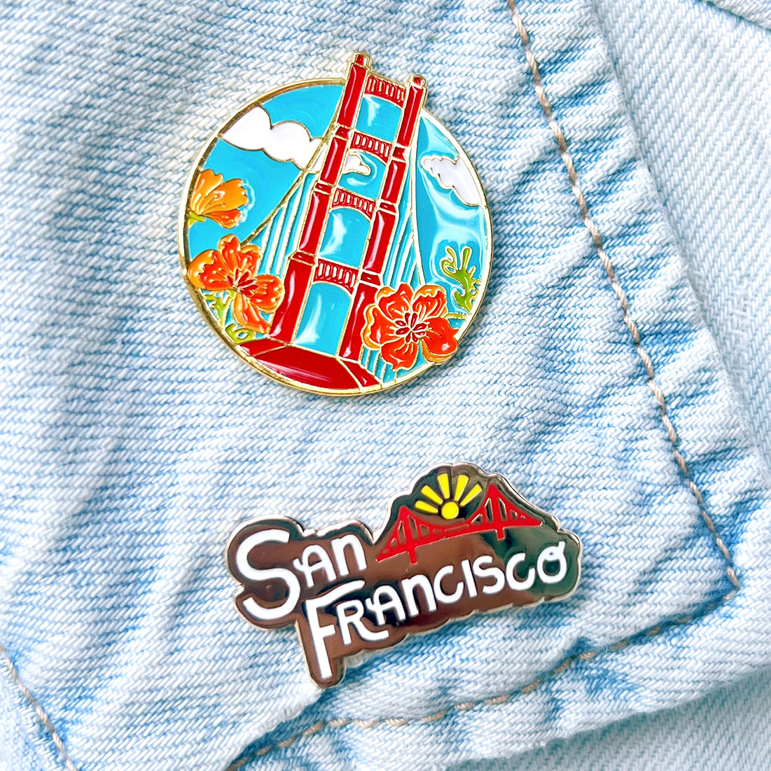San Francisco lettering hard enamel pin shown with a Golden Gate Bridge pin on denim.